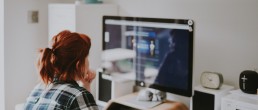 Une femme rousse est assise devant son écran d'ordinateur