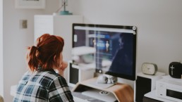 Une femme rousse est assise devant son écran d'ordinateur